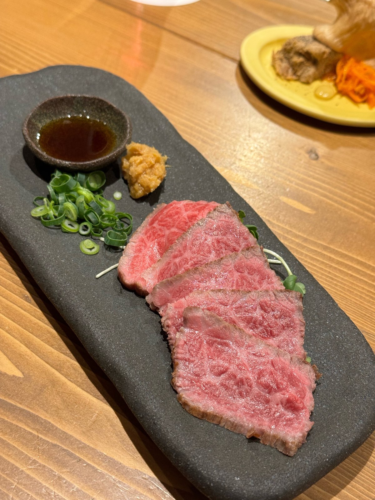 薬味とたれを添えて薄く並べた鉄板焼みついのお肉料理
